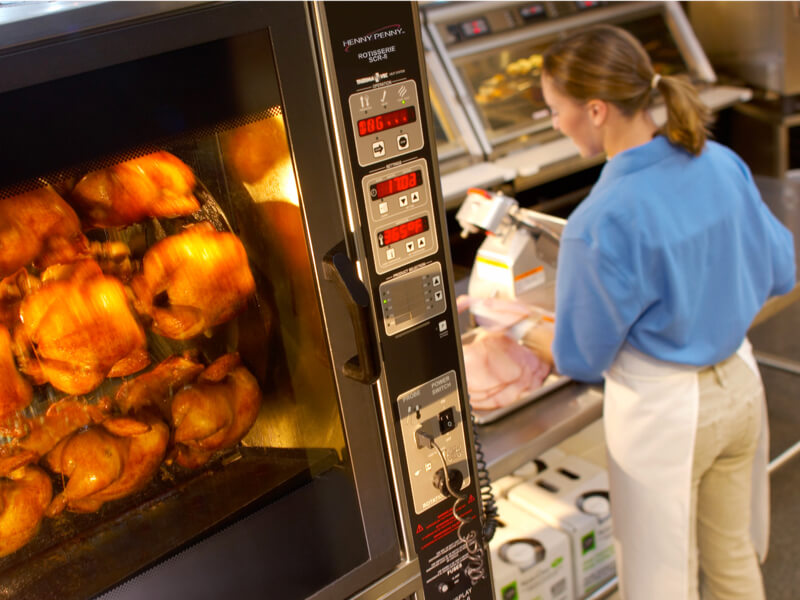 Woman putting chicken into warmer cabinet