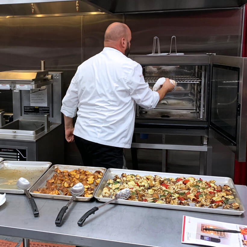 Commercial food service employee putting food into a heating cabinet