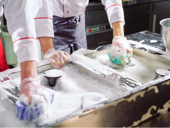 Woman cleaning open deep fryer