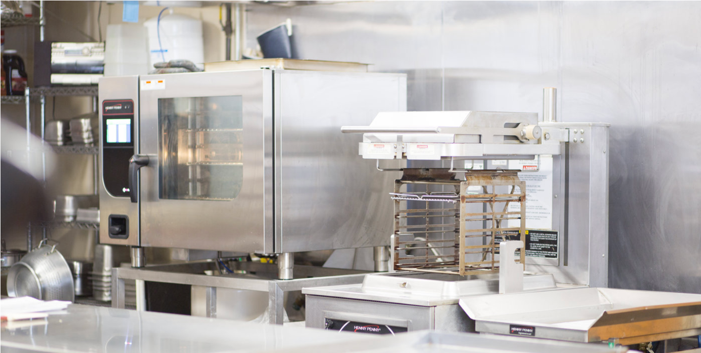 Foodservice equipment, like Henny Penny combi oven and a Henny Penny fyrer, in a kitchen.